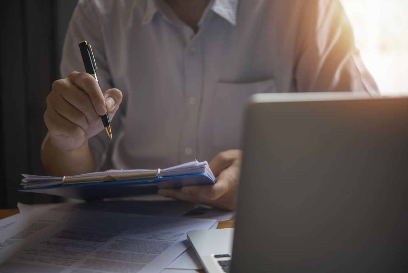 Main tenant un stylo sur des documents et un rapport